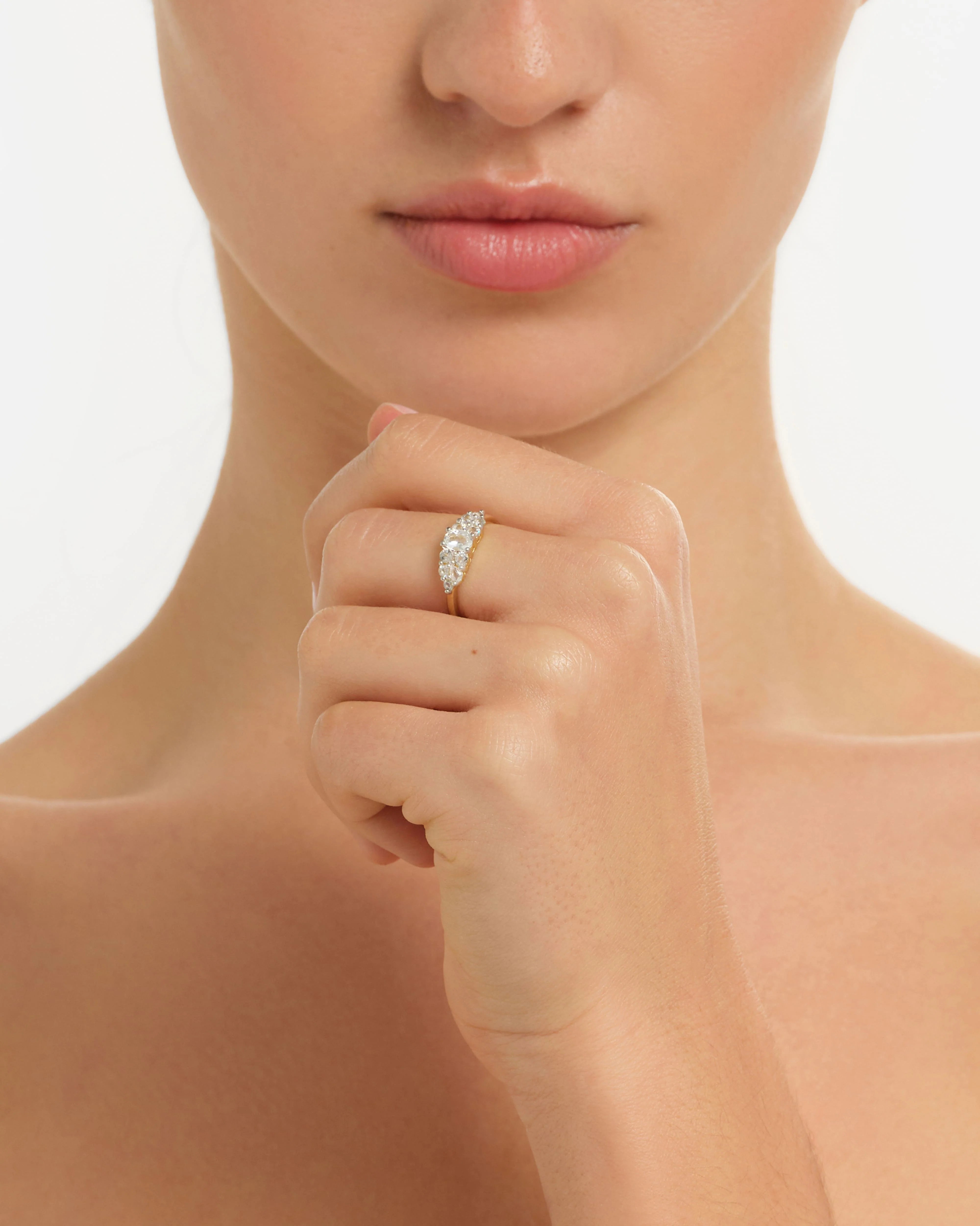 Close-up of a hand wearing a diamond ring on a neutral background